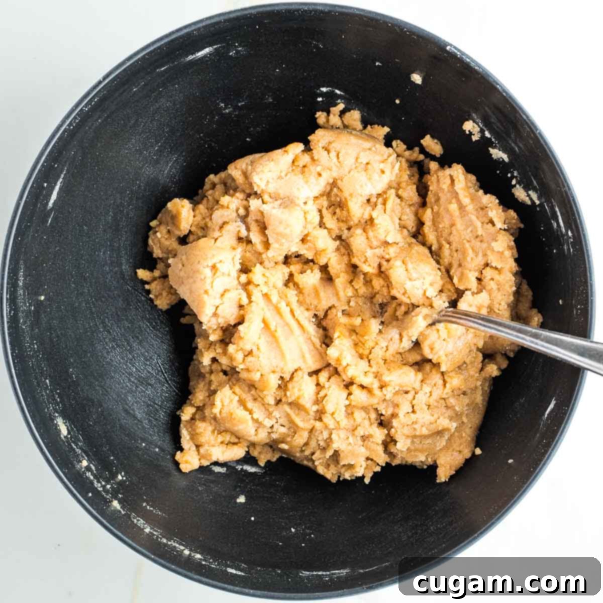 Lumpy, sticky pie dough in a black bowl, demonstrating the correct consistency.