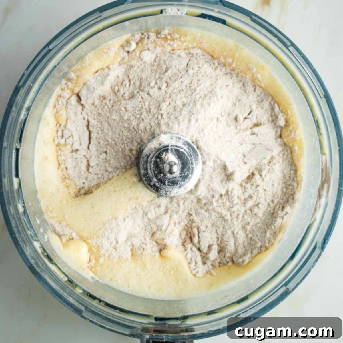 Golden Sweet Round Challah 11 Flour sprinkled on top of yeast and egg mixture in the bowl of a food processor.