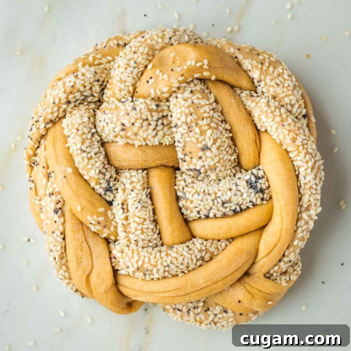 Golden Sweet Round Challah 32 Round loaf of braided challah dough with sesame and poppy seeds.