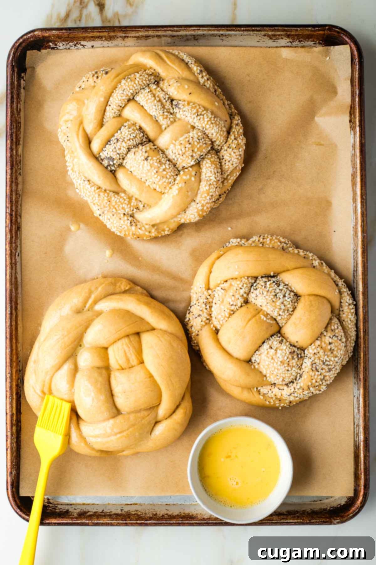 Golden Sweet Round Challah 41 Brushing egg wash on braided round loaves of challah bread.