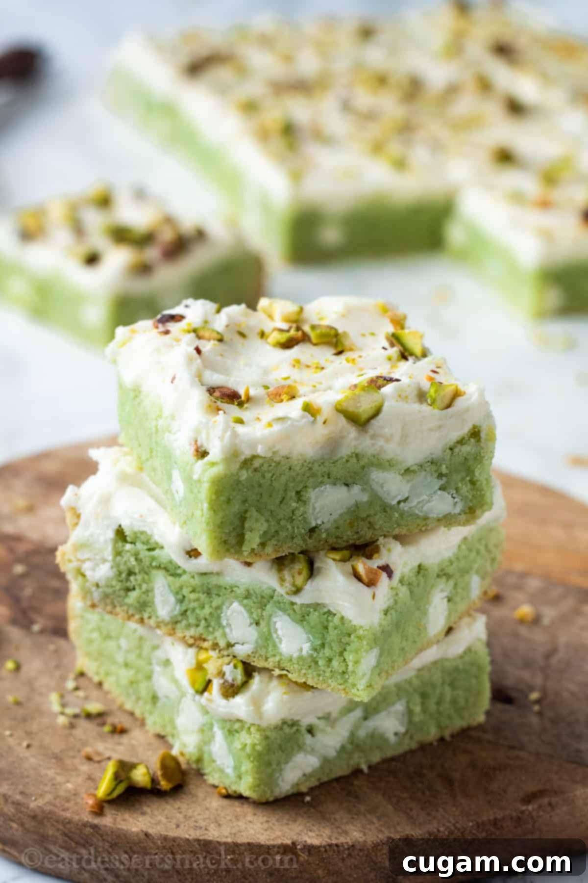 Stack of 3 frosted pistachio bars on wood board. 