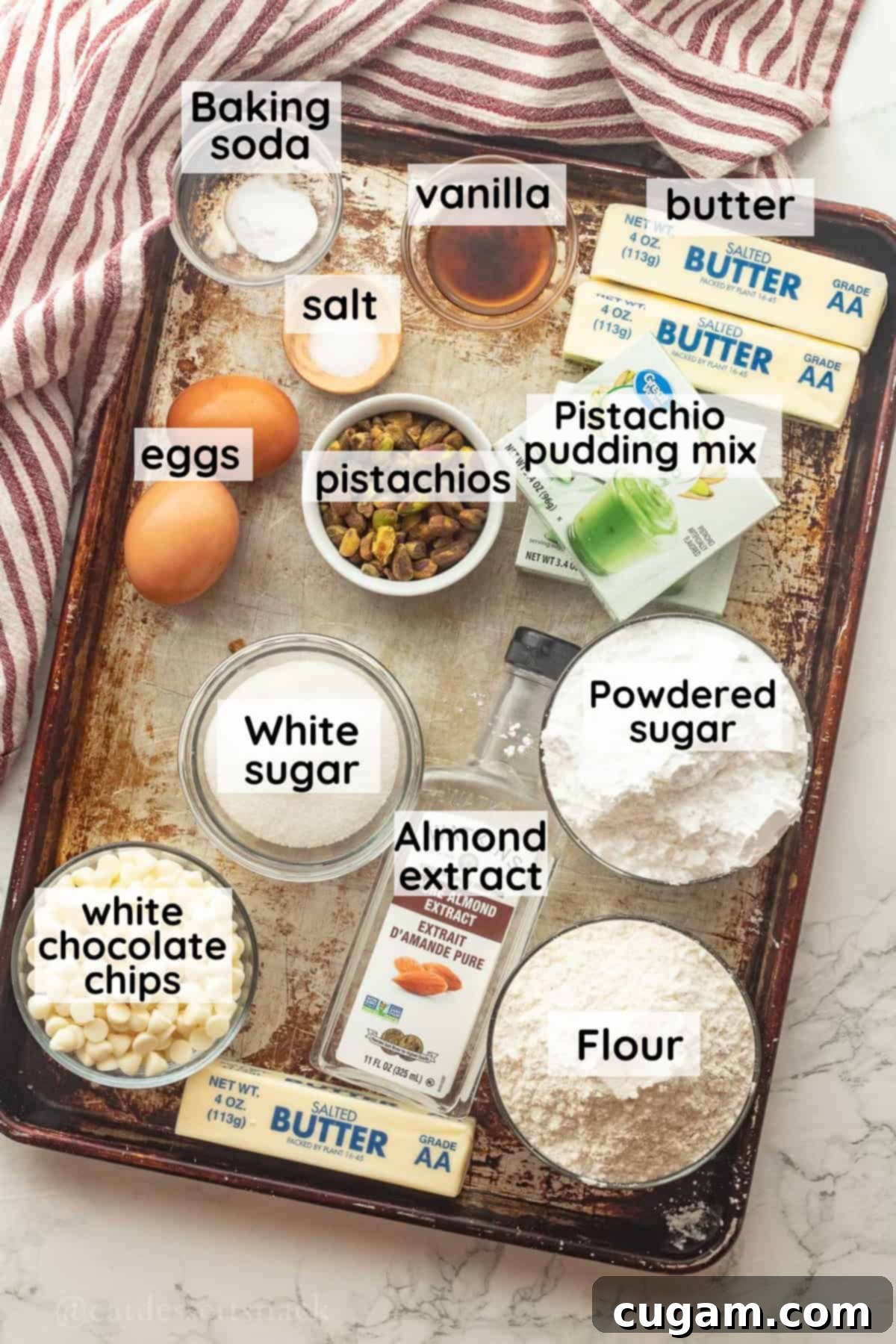 Ingredients for pistachio bars on a metal baking sheet in glass bowls labeled.