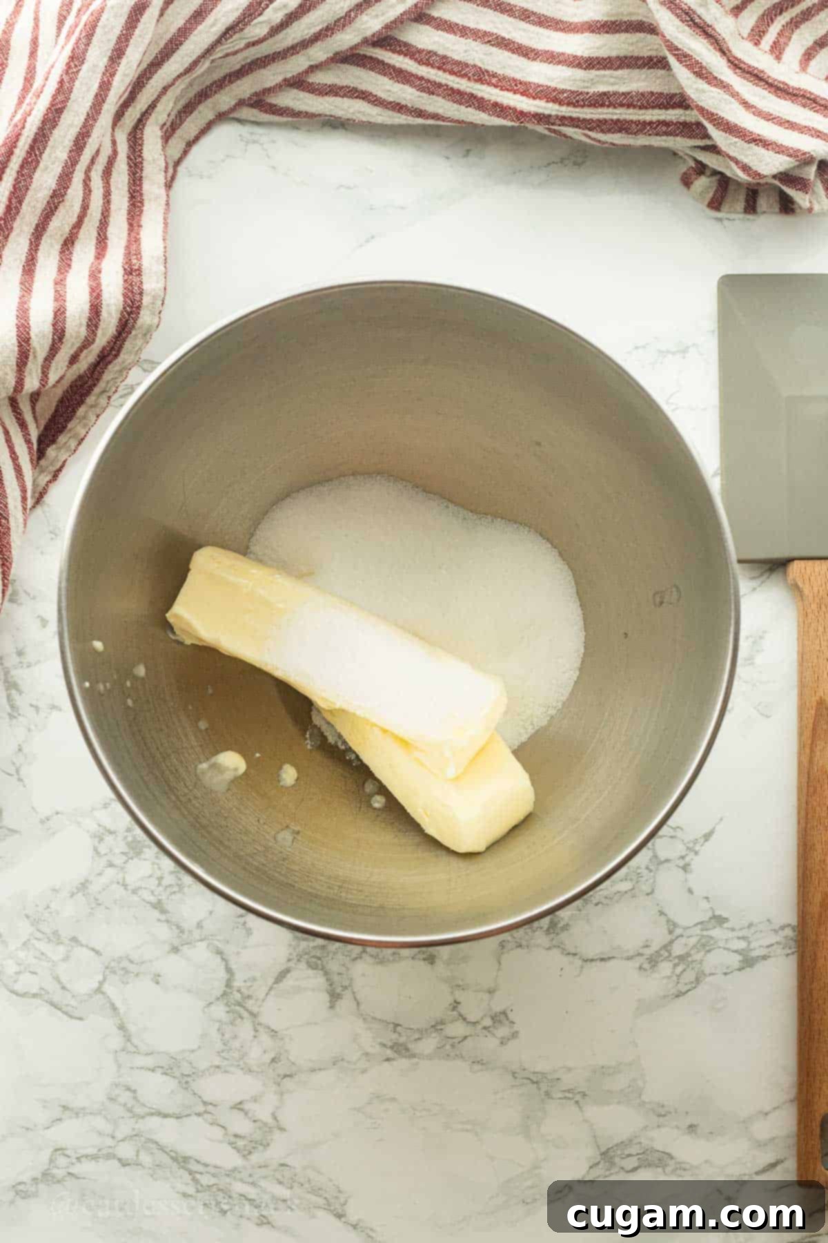 Butter and sugar in a metal bowl on marble countertop.