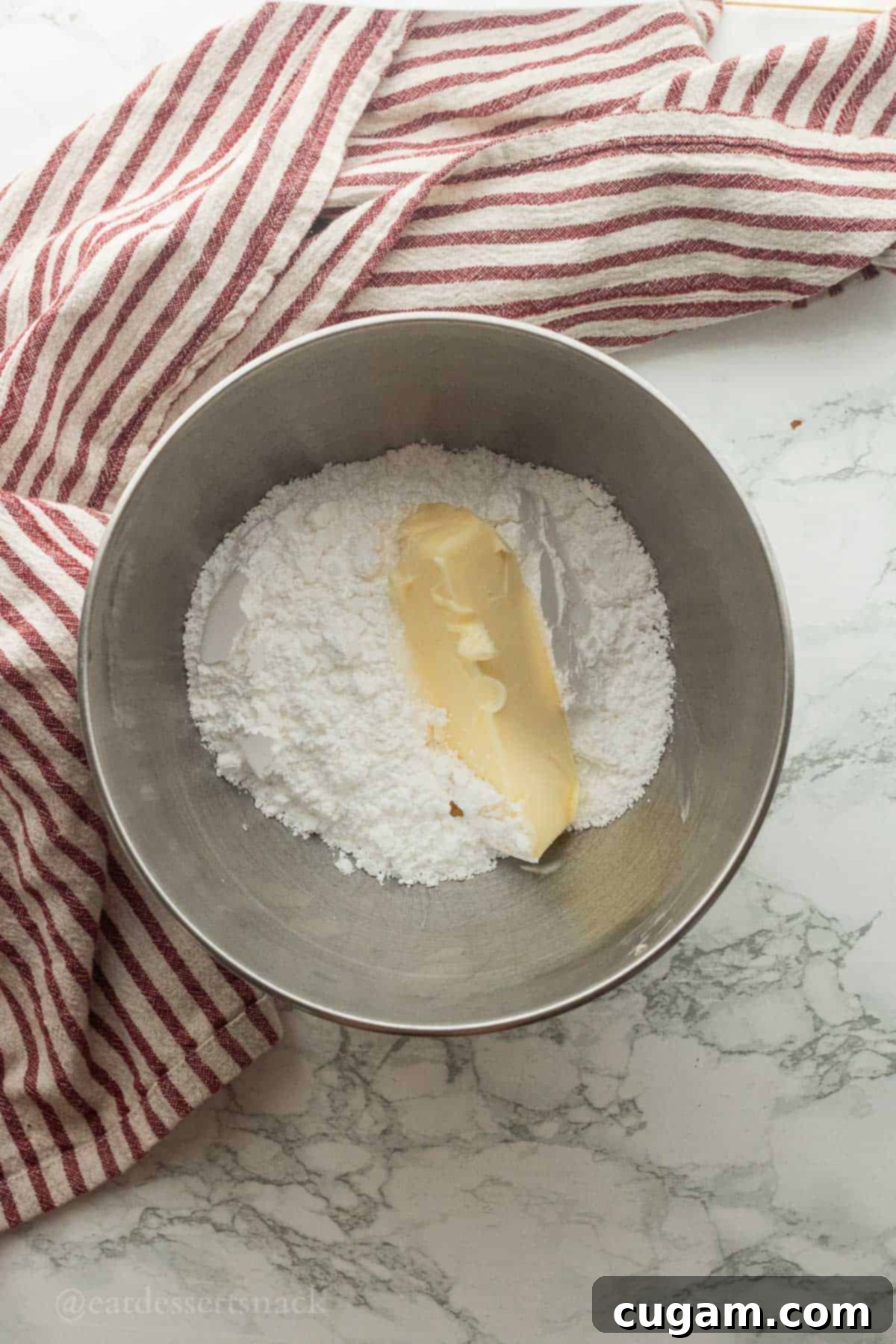 Butter and powdered sugar in metal mixing bowl.