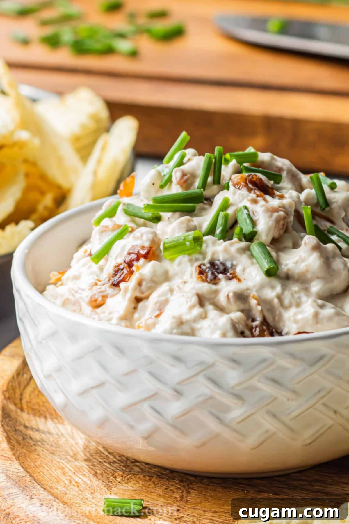 white bowl of caramelized onion dip on wood platter. 