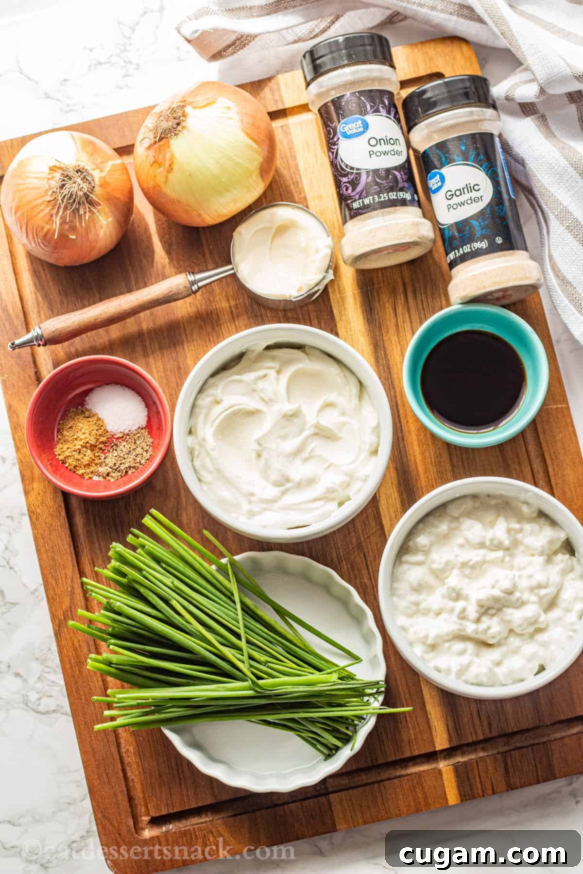 Ingredients for caramelized onion dip on wood cutting board. 