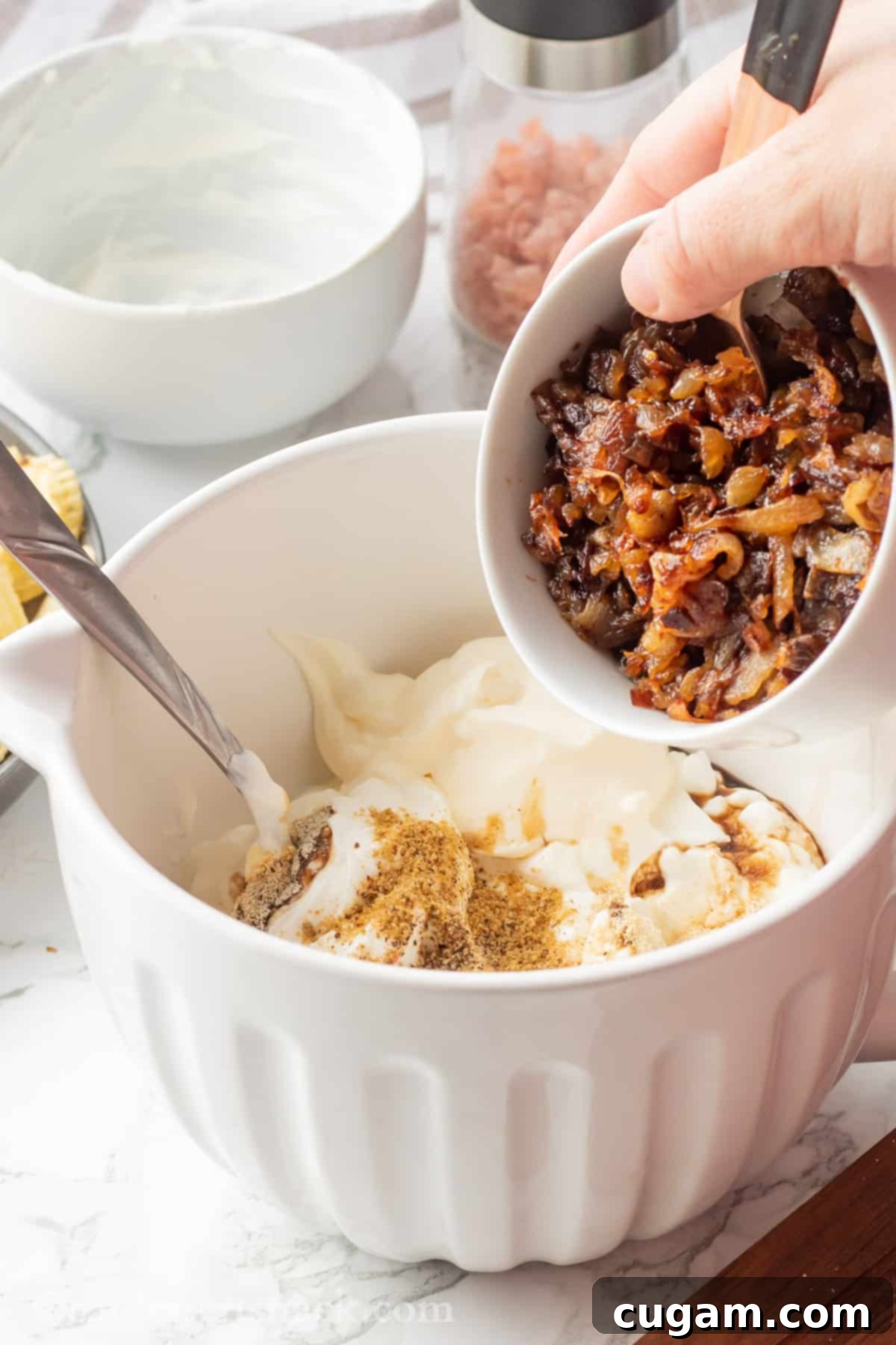 Pouring caramelized onions into white bowl. 