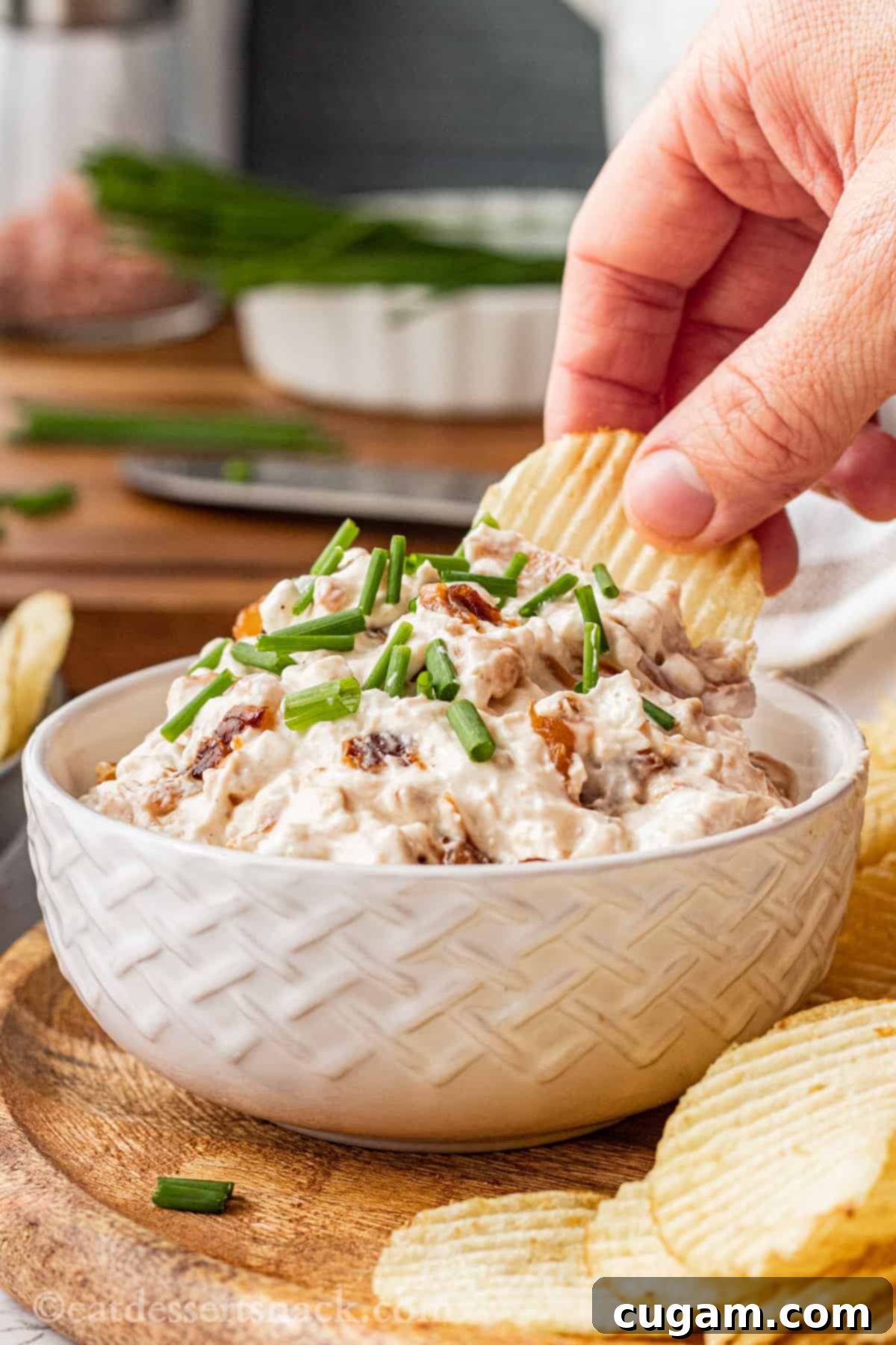 Chip dipping into white bowl of caramelized onion dip. 