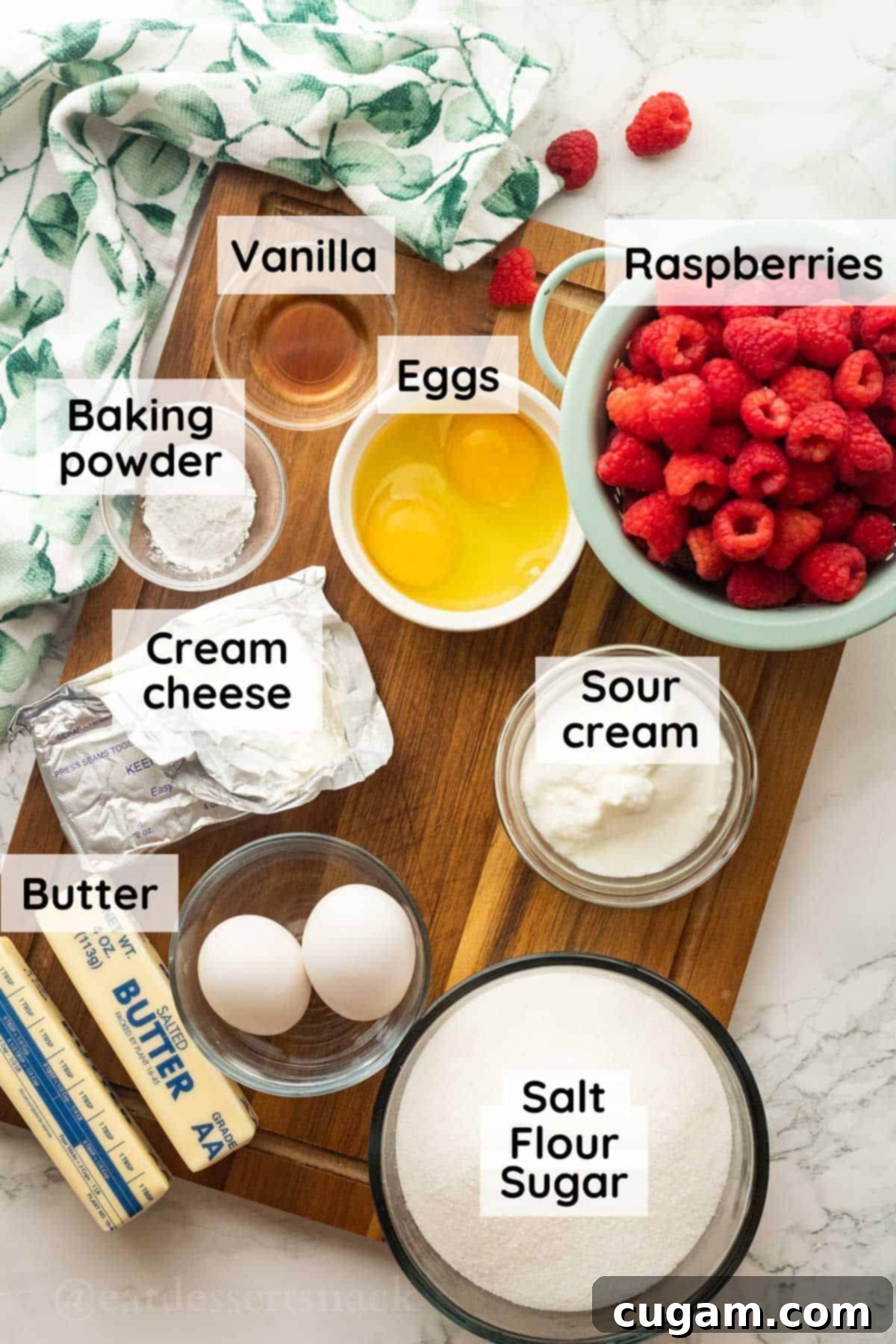 Labeled ingredients of raspberries and cream bars, beautifully arranged on a wooden cutting board in glass bowls, ready for baking.