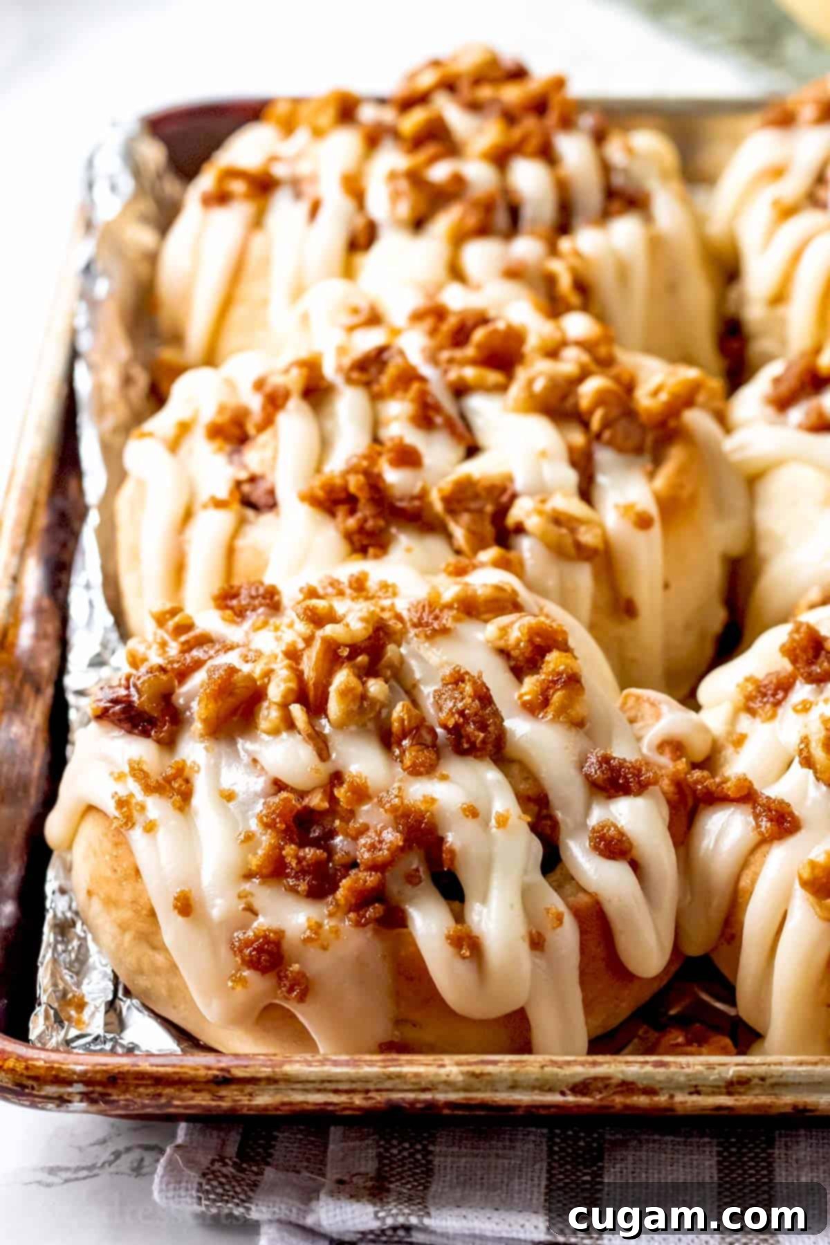 Freshly baked and generously frosted banana cinnamon rolls nestled together in a metal baking pan.