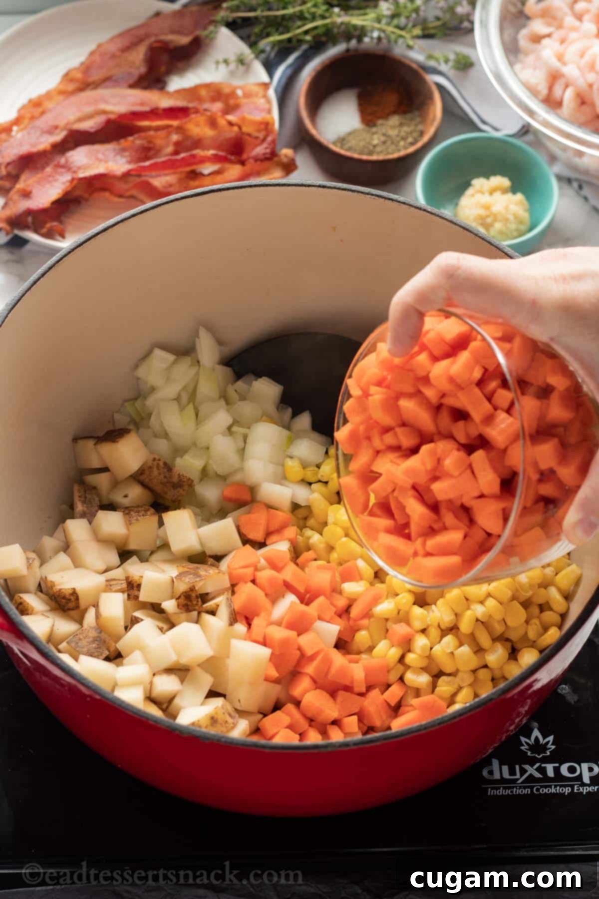 Carrots, potatoes, corn, and onions simmering in a large cooking pot with butter.