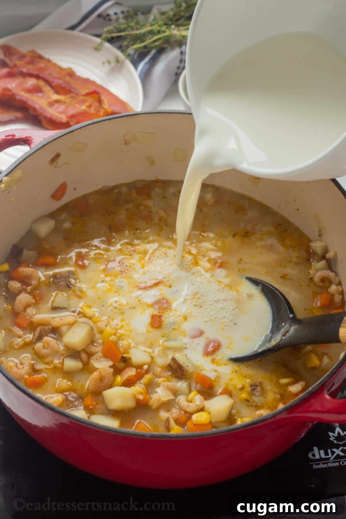 Pouring a milk and flour mixture (slurry) into a red pot of simmering corn and shrimp chowder.