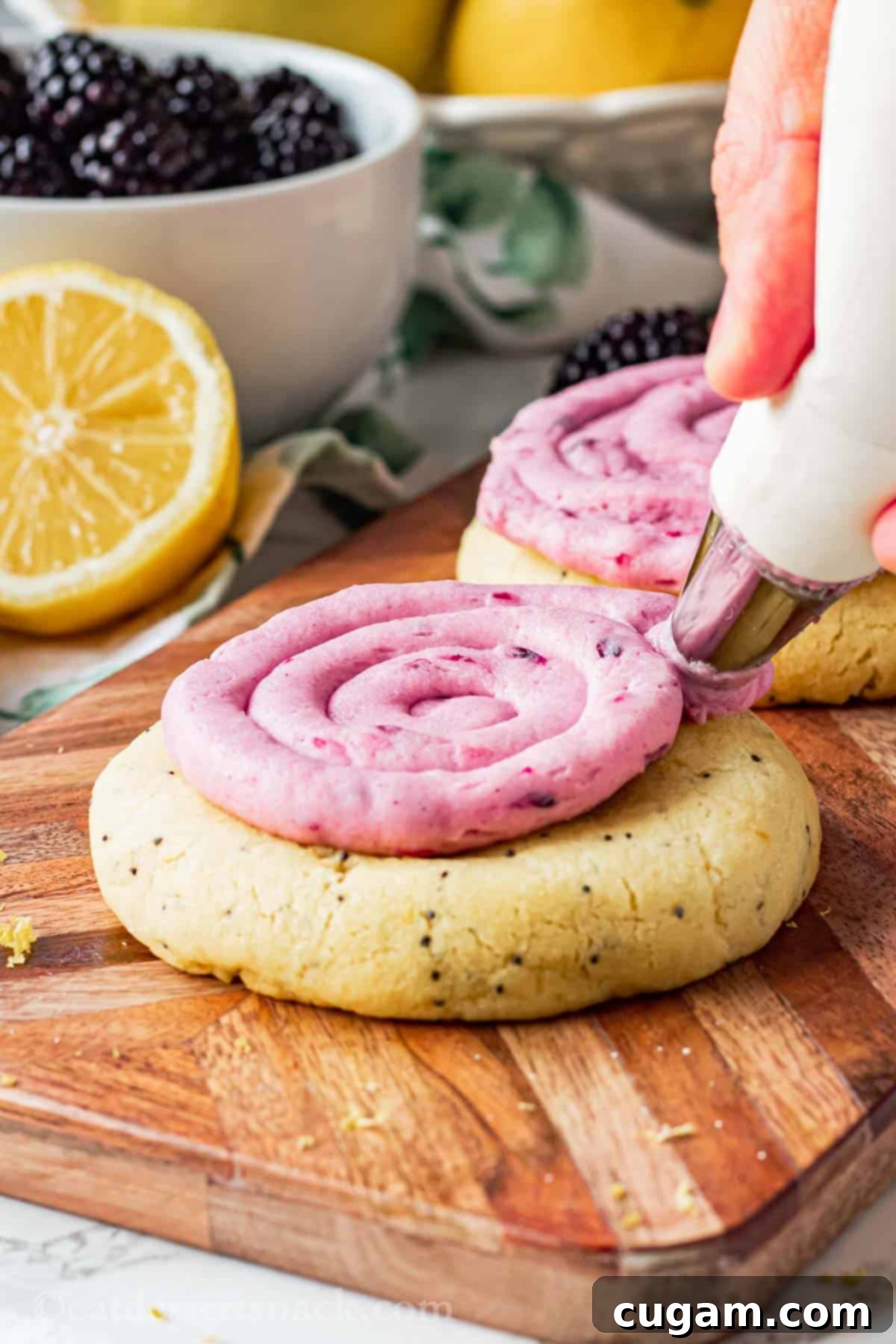 Piping blackberry frosting onto a baked lemon poppyseed cookie. 