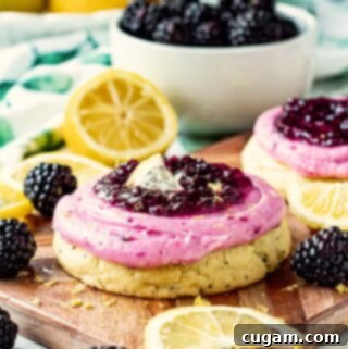Baked Lemon Blackberry Cookie with frosting on wooden cutting board with lemon slices and blackberries.