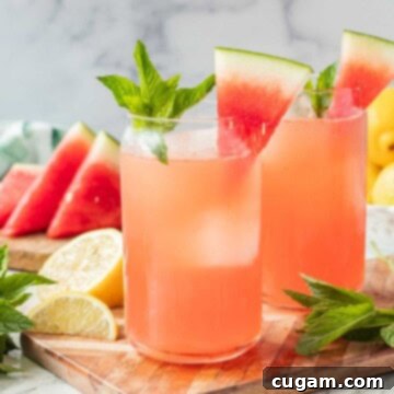 Glass of watermelon mint lemonade on wood cutting board with slice of watermelon and sprig of mint on top.