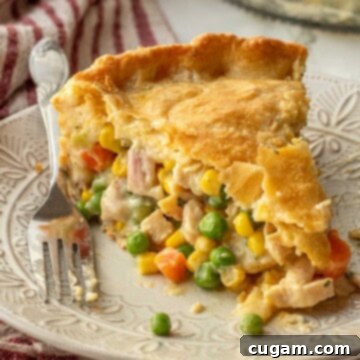 Quick Chicken Pot Pie 12 Slice of baked chicken pot pie on white plate with fork.