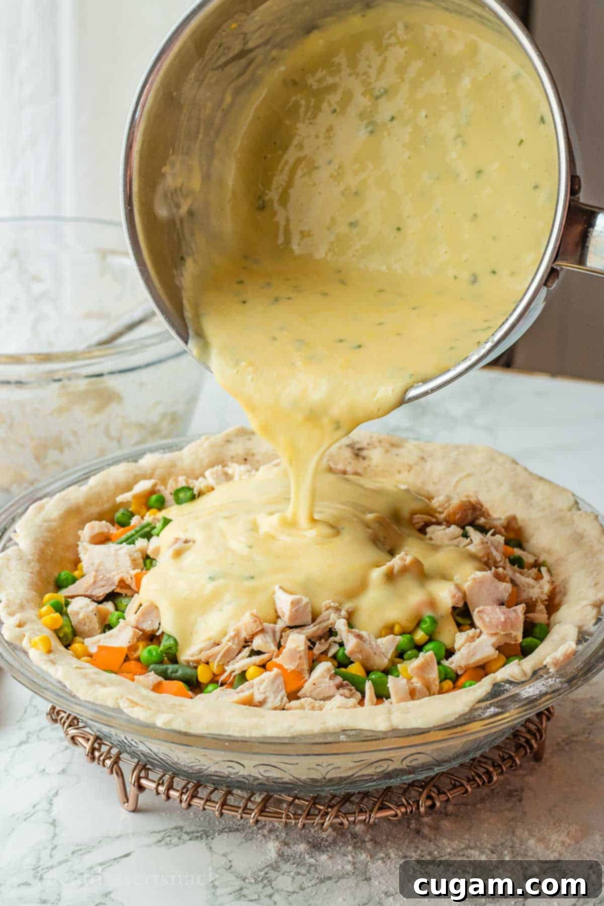 Quick Chicken Pot Pie 8 Pouring chicken gravy into chicken pot pie crust over veggies.