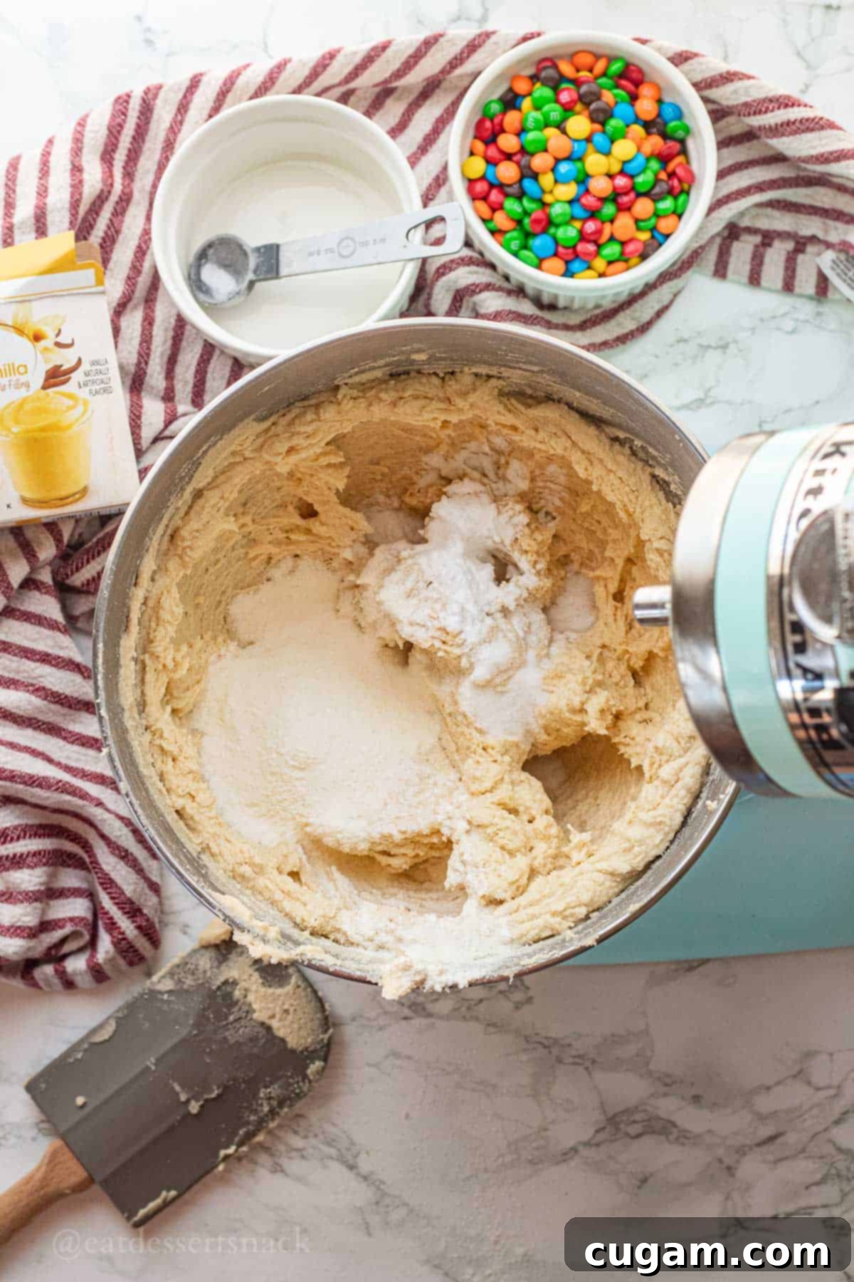 Vanilla pudding mix and baking soda in metal mixing bowl with creamed butter and sugar.