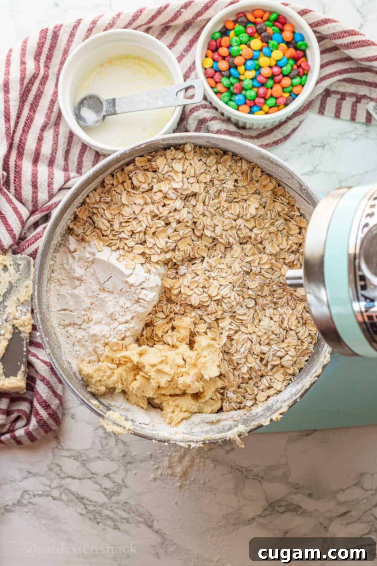 Oats, flour, and creamed butter and sugar in metal mixing bowl.
