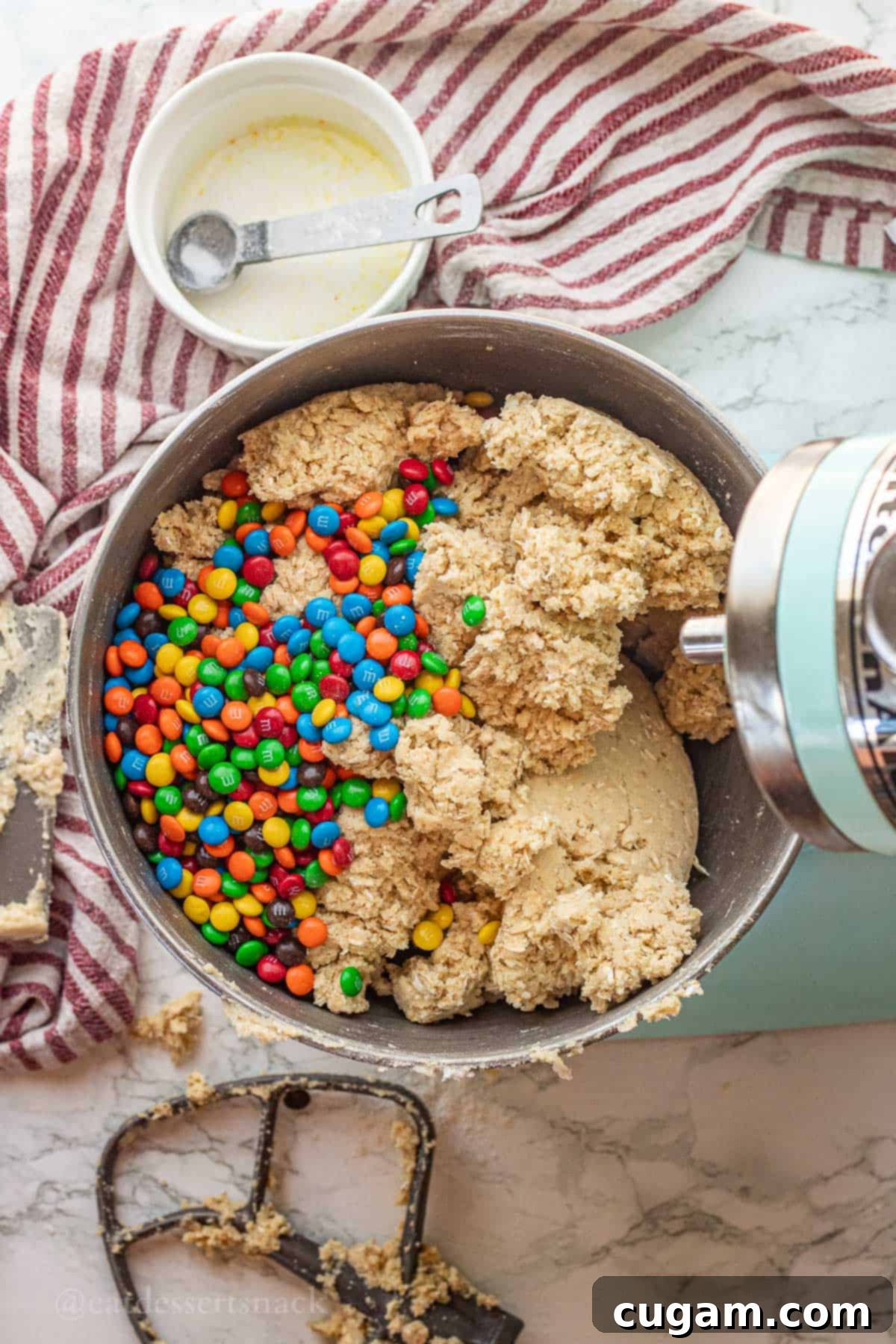 Raw oatmeal cookie dough with m&ms in metal mixing bowl.