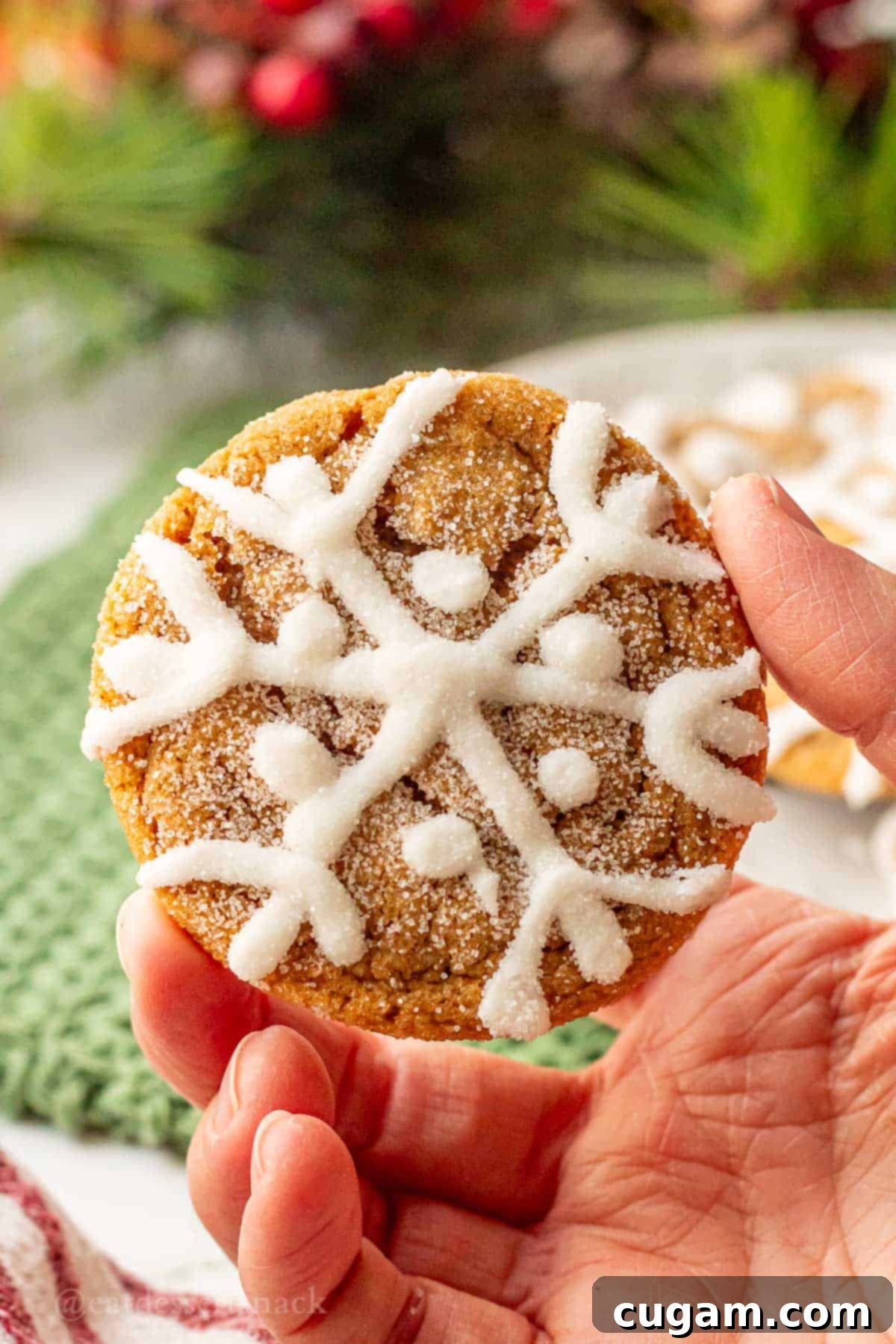 Hand holding baked iced ginger cookie.