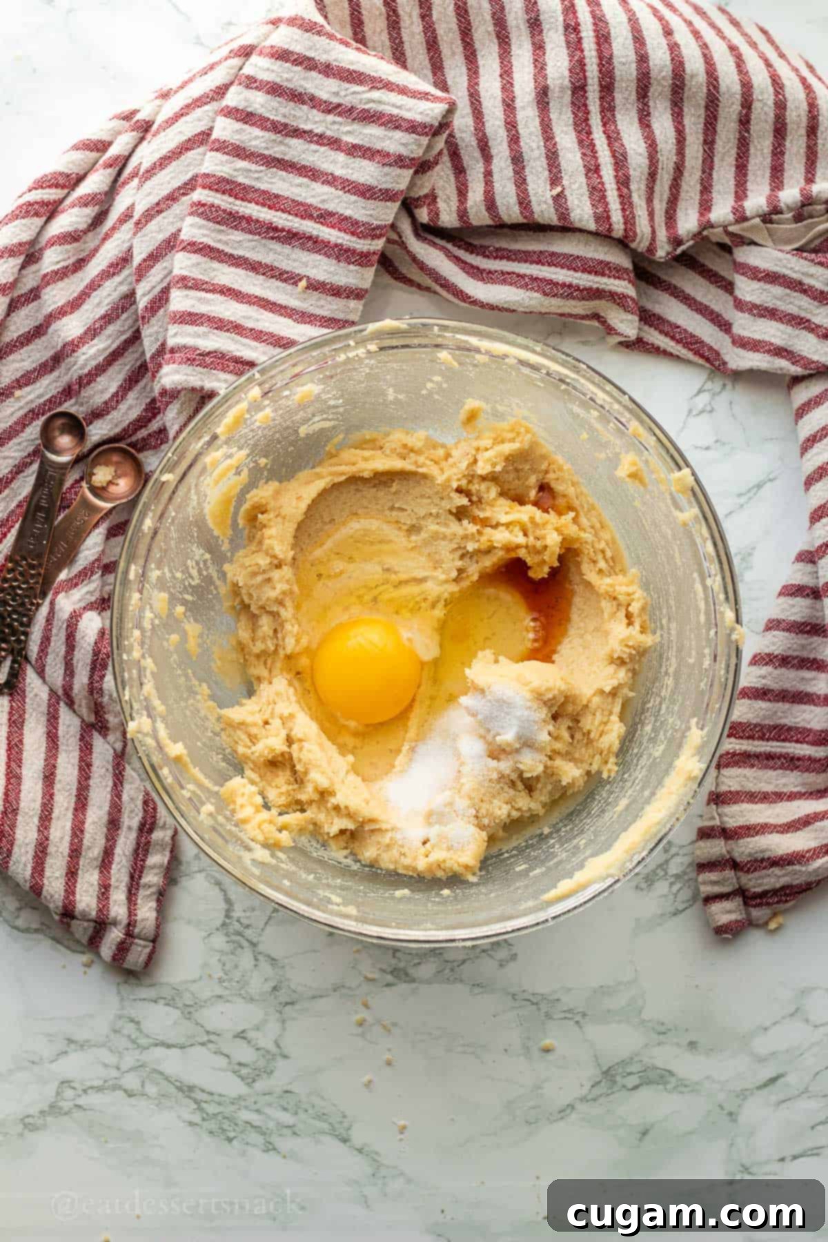 Egg, vanilla, and salt in glass bowl with creamed butter and sugar.