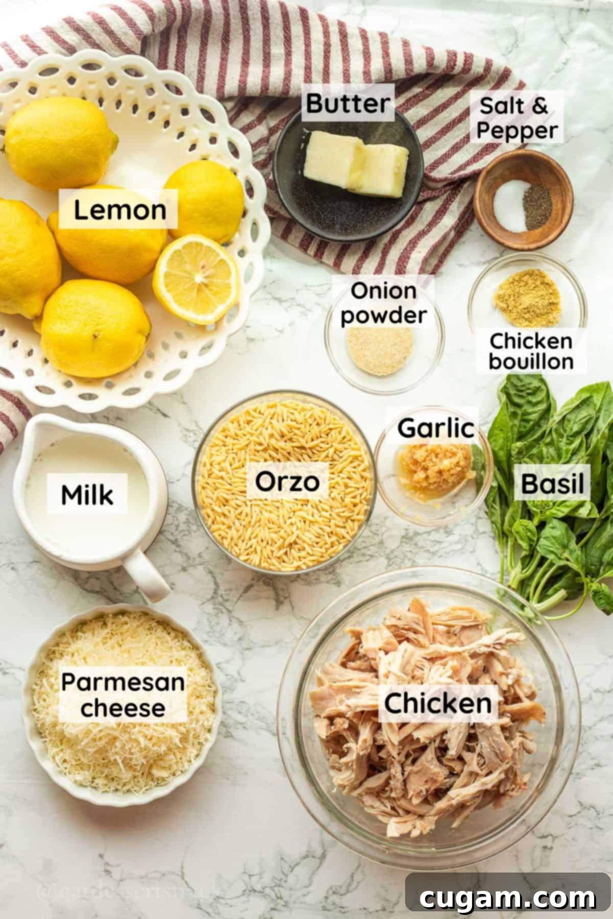 Lemon chicken orzo ingredients labeled in glass dishes on marble countertop.
