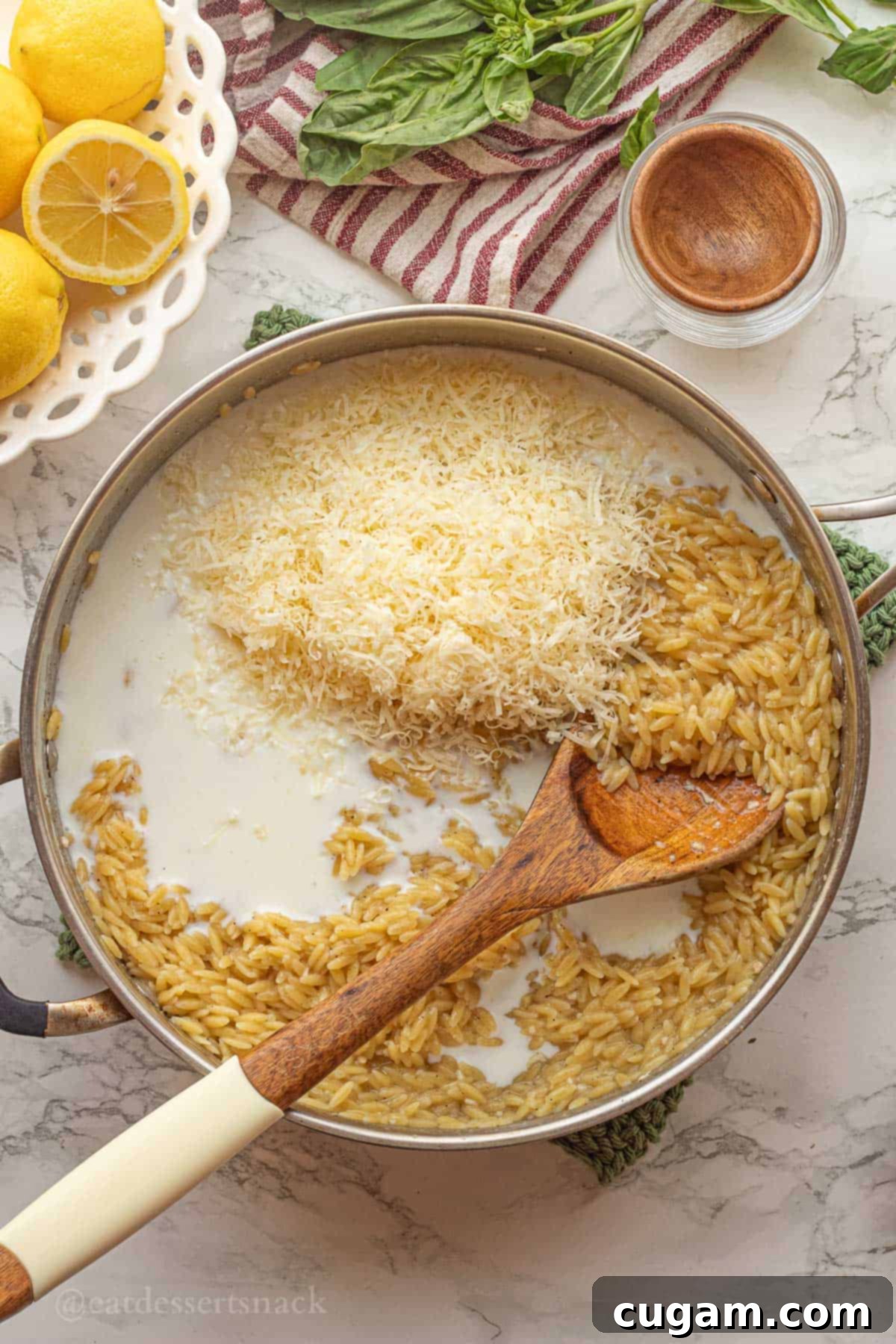 Shredded parmesan cheese in pan of cooked orzo.