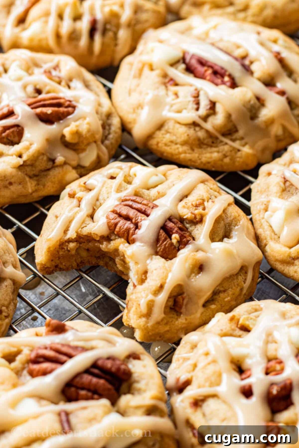 Baked Maple Cookies on metal pan with bite out of one. Soft and chewy maple pecan cookies with white chocolate and maple icing.