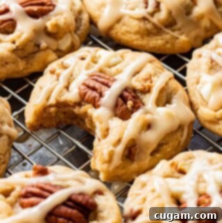 Baked Maple Cookies on metal pan with bite out of one. Soft and chewy maple pecan cookies with white chocolate and maple icing.