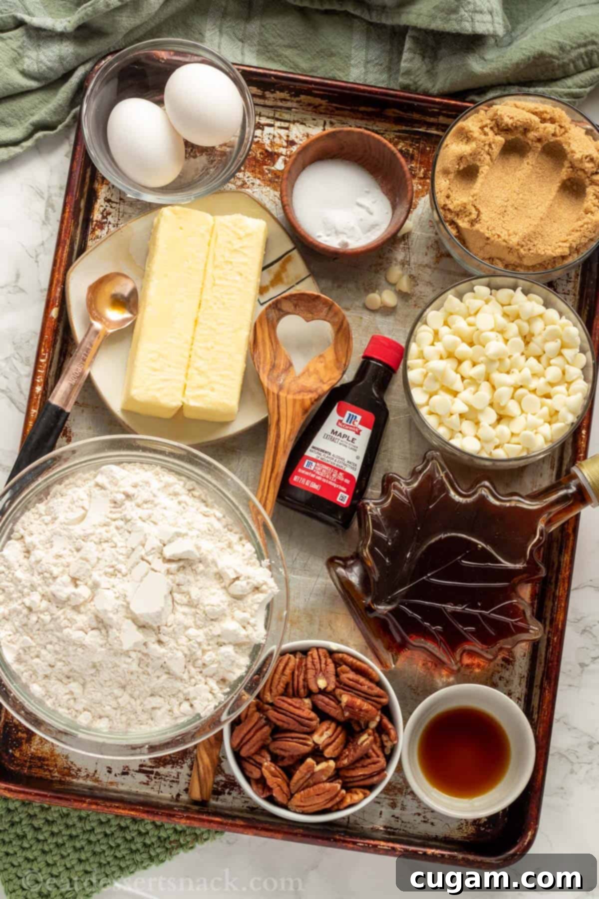 Ingredients for Maple Cookies on metal baking sheet. Butter, brown sugar, eggs, maple syrup, maple extract, flour, white chocolate chips, pecans.