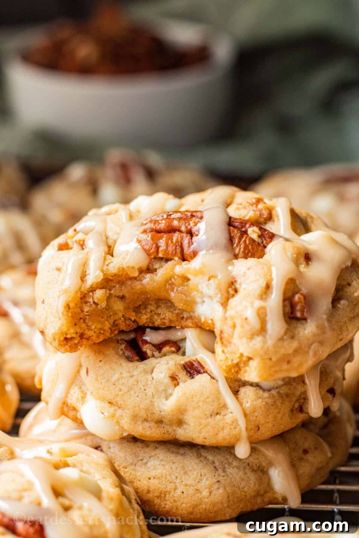 Stack of 3 iced maple cookies with bite out of top one. Delicious maple pecan white chocolate cookies.
