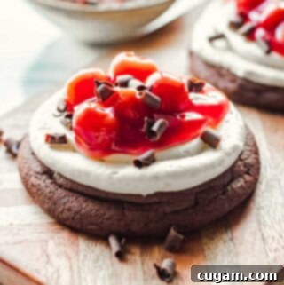 Baked cherry chocolate cheesecake cookie with chocolate shavings on wood board.