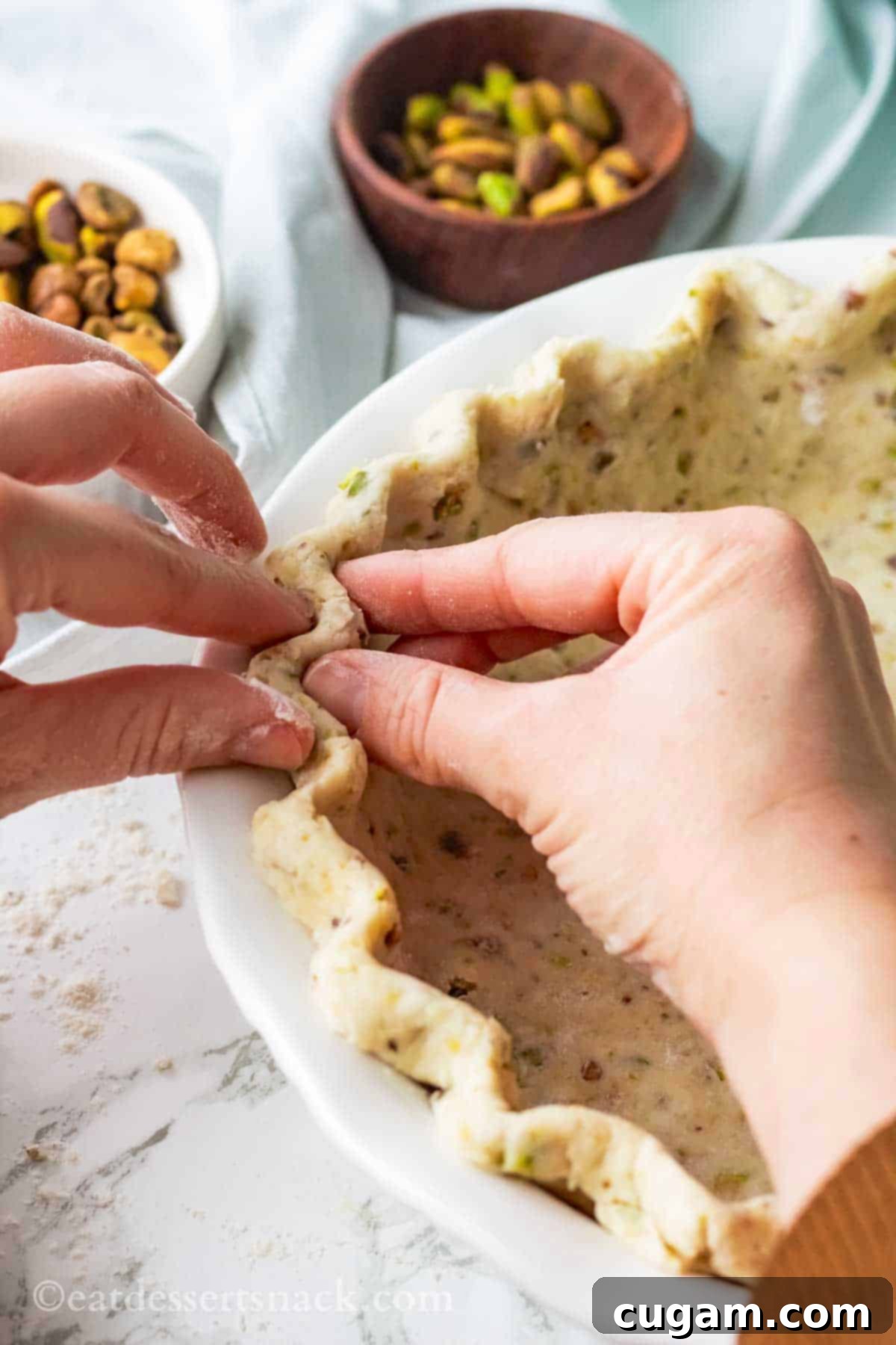 Velvet Pistachio Dream Pie 11 Hands carefully crimping the edges of a raw pistachio pie crust in a 9-inch white pie dish.