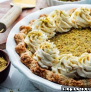 Velvet Pistachio Dream Pie 15 Baked Pistachio Custard Pie in a white pie dish with whipped cream on top, ready to serve.