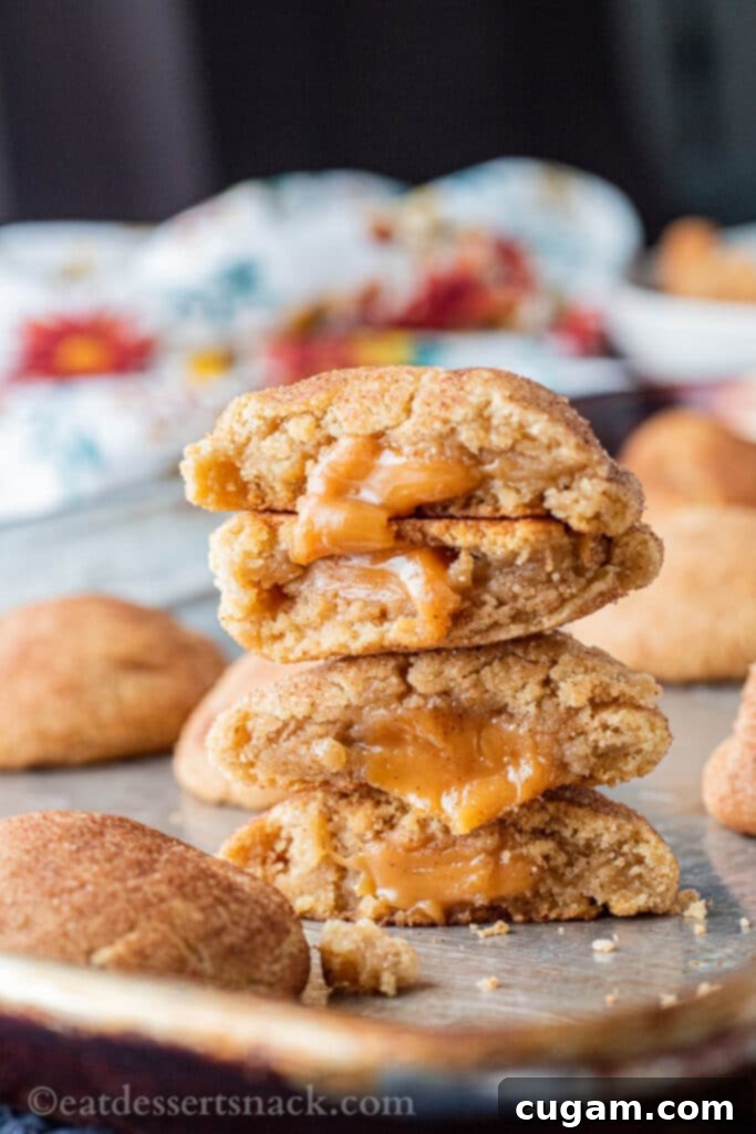 Stack of four baked halves of caramel stuffed snickerdoodles on a metal pan.