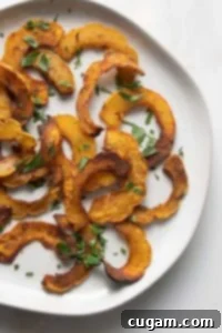 Round plate with half moon shaped roasted delicata squash sprinkled with parsley.