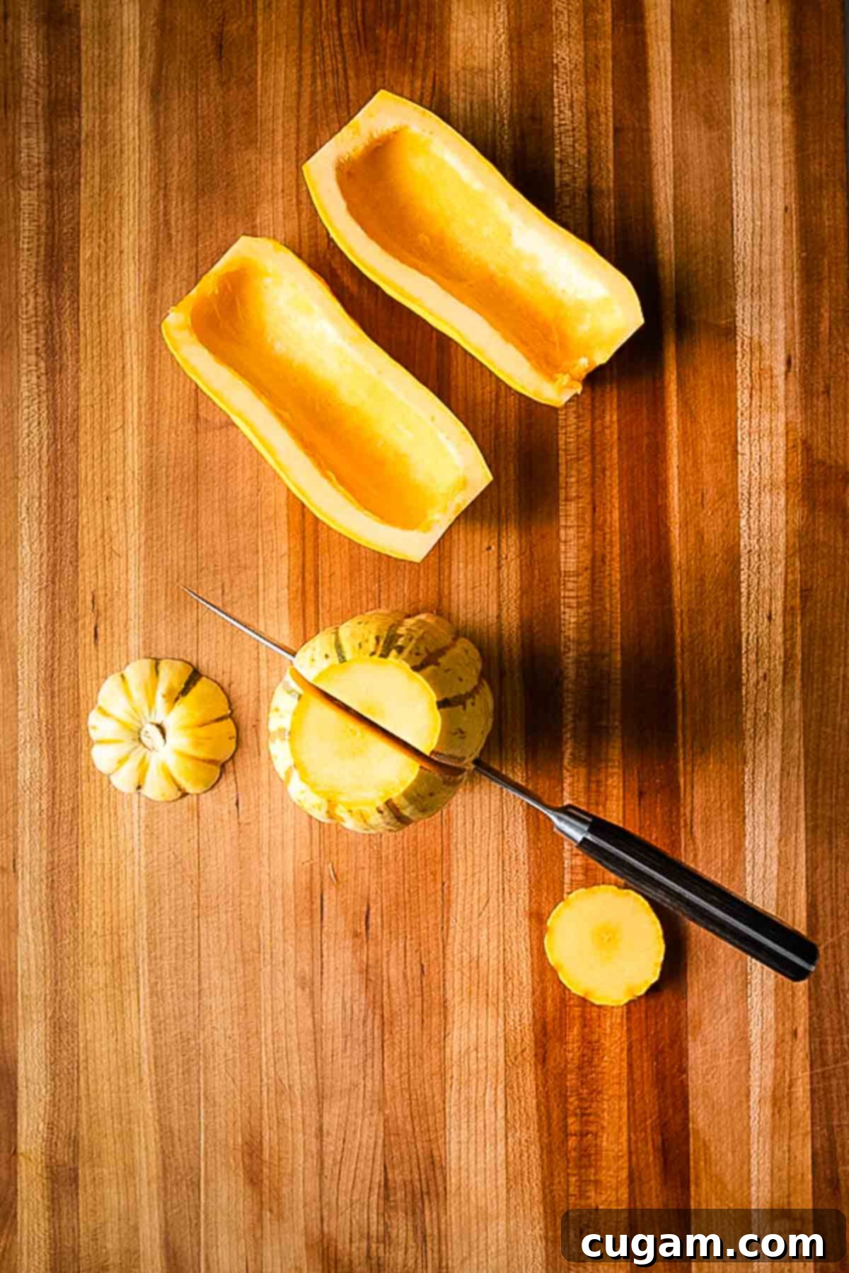 Close-up of delicata squash seeds being scooped out with a spoon.