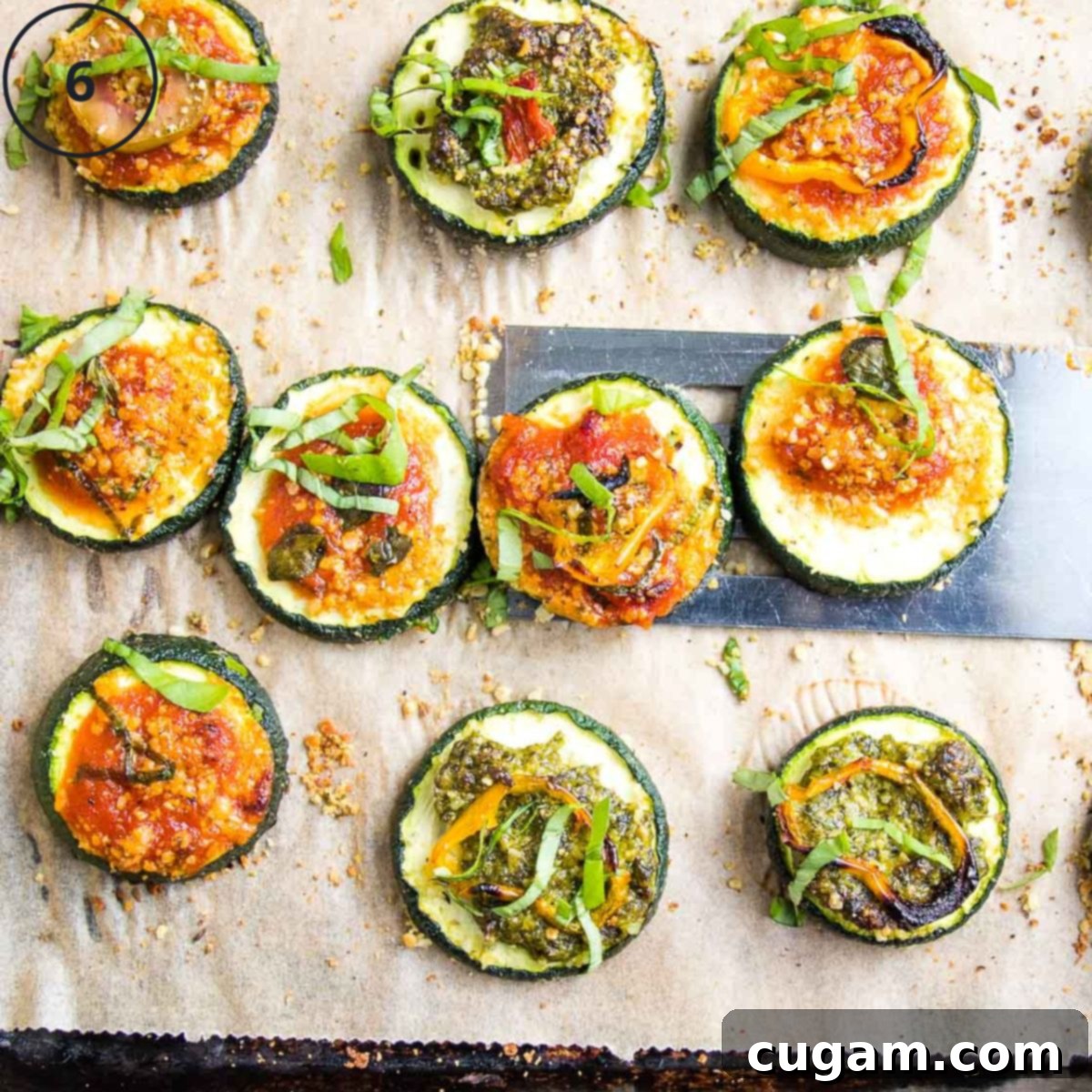 Quick Zucchini Pizza Bites 10 Zucchini Pizza Bites with pesto or marinara and assorted toppings, on a baking tray.