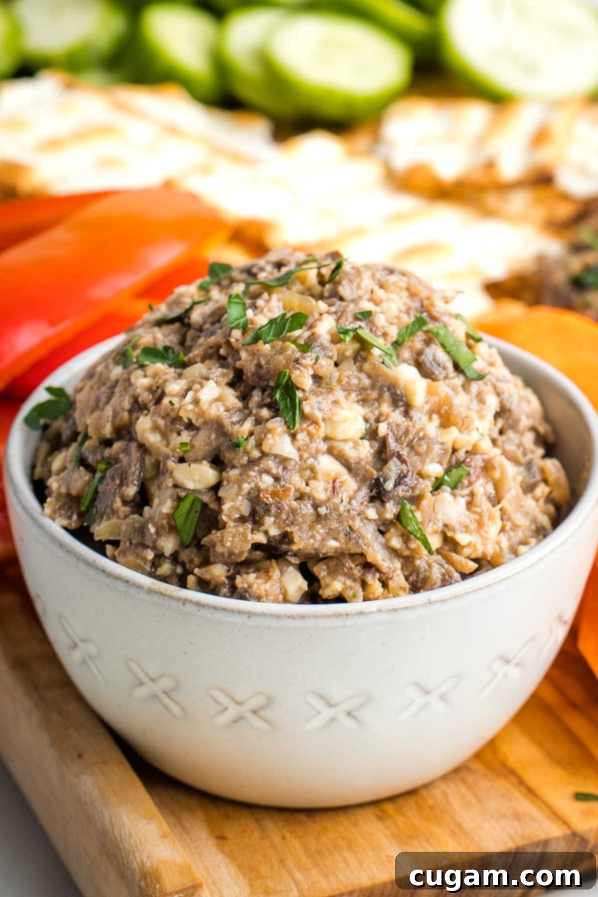 Close up of a bowl of rich, brown vegetarian chopped liver, featuring visible pieces of sautéed mushrooms, caramelized onions, crunchy walnuts, and creamy hard-boiled eggs, highlighting its savory texture.
