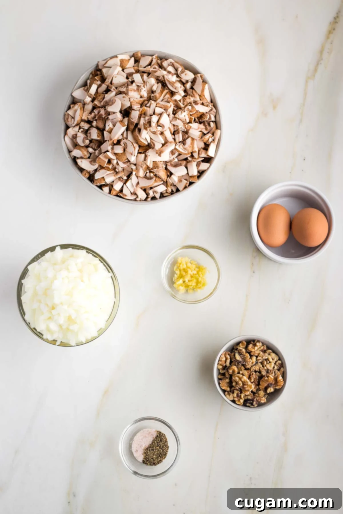 A collection of prepped ingredients laid out: finely chopped mushrooms, diced onions, minced garlic, whole walnuts, peeled hard-boiled eggs, and small bowls of salt and pepper, all ready for the recipe.