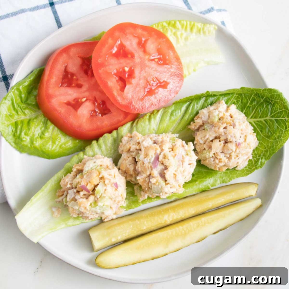 Large romaine leaves with scoops of vegan tuna, tomato slices and pickles.
