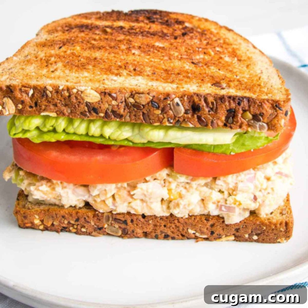 Side view of a vegan tuna sandwich with lettuce and tomatoes on toast.