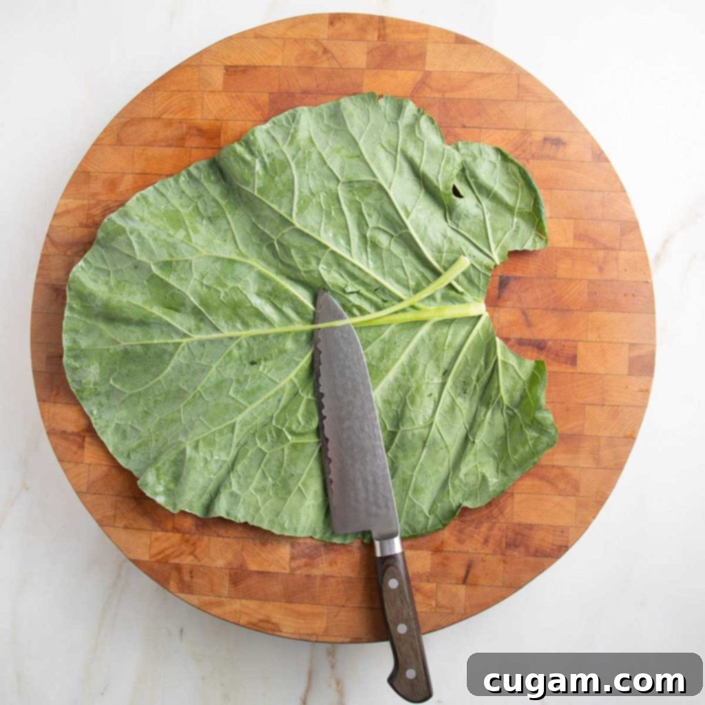 Large collard green leaf on a cutting board with chef's knife.