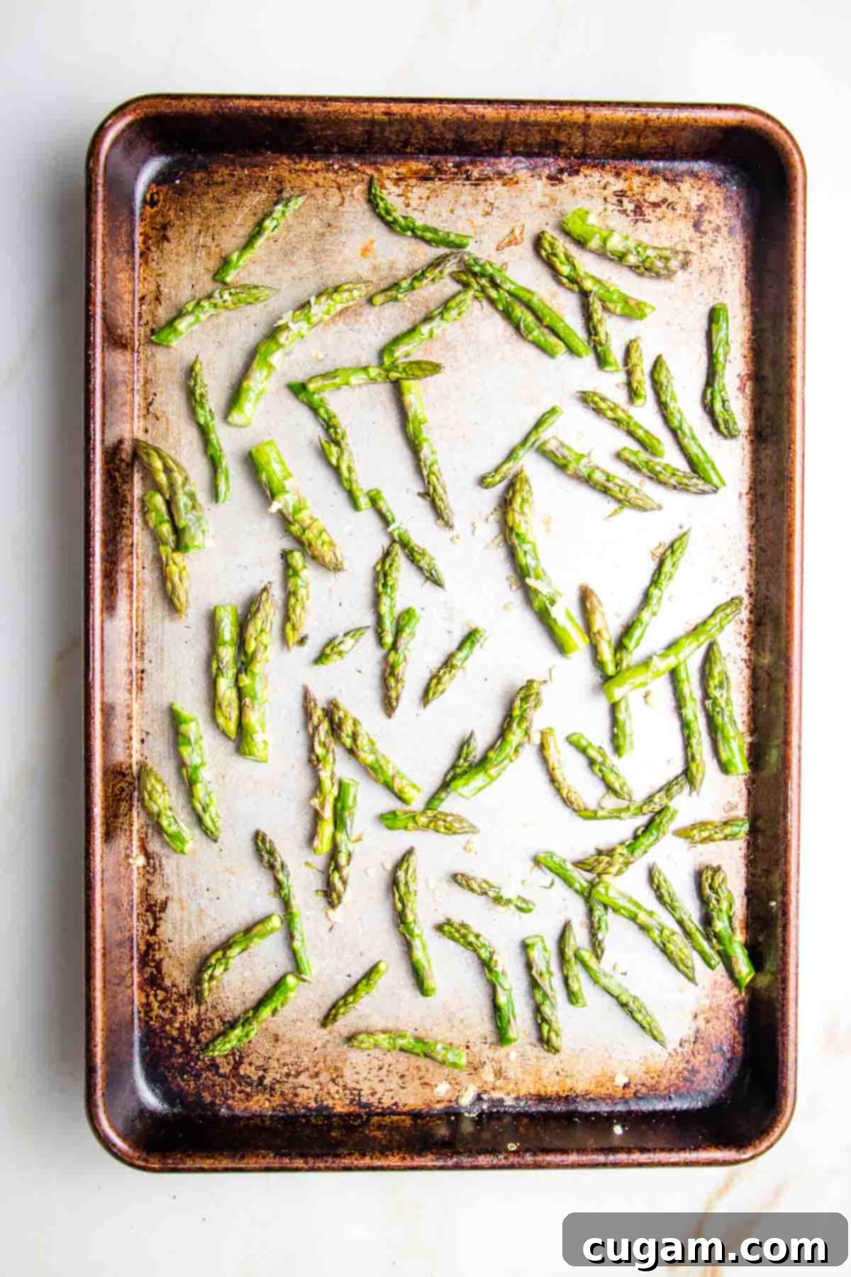 A baking tray filled with vibrant green, perfectly roasted asparagus tips, showcasing their appealing color and slight char.