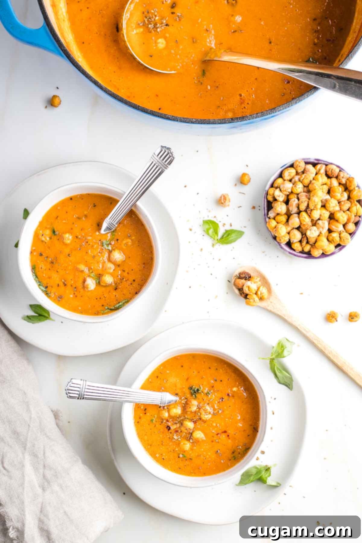 Creamy Dairy-Free Tomato Soup Recipe 2 Bowls of creamy dairy-free tomato soup with crunchy roasted chickpeas and a side bowl with more chickpeas.