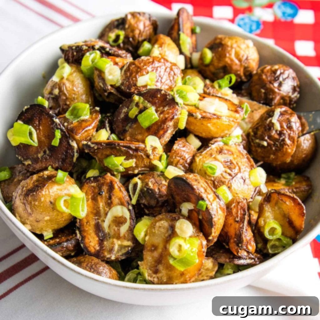 A vibrant bowl of grilled potato salad, generously sprinkled with fresh scallions, sits on a cheerful red and white checkered background, highlighting the fresh, appealing presentation.