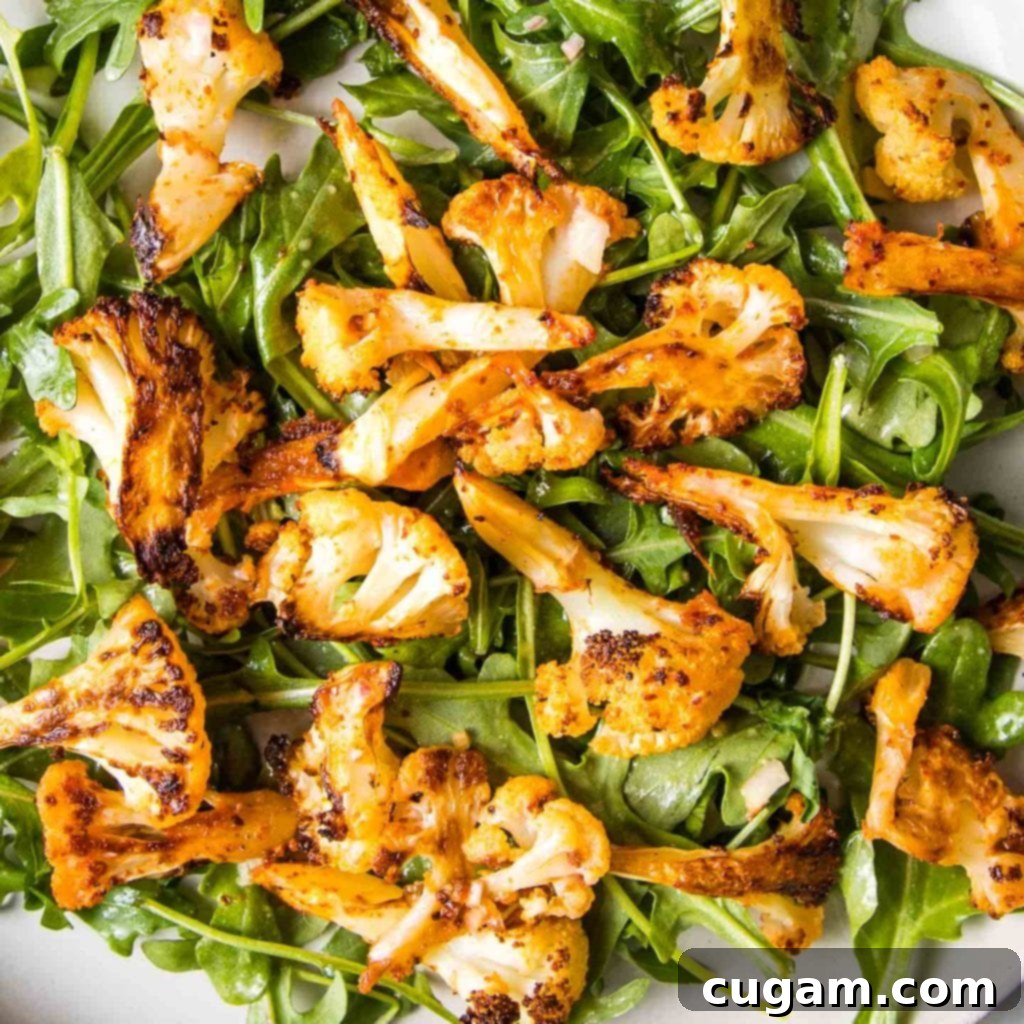 An elegantly plated serving of paprika roasted cauliflower and arugula salad, showcasing the vibrant green and golden textures, ready for enjoyment.