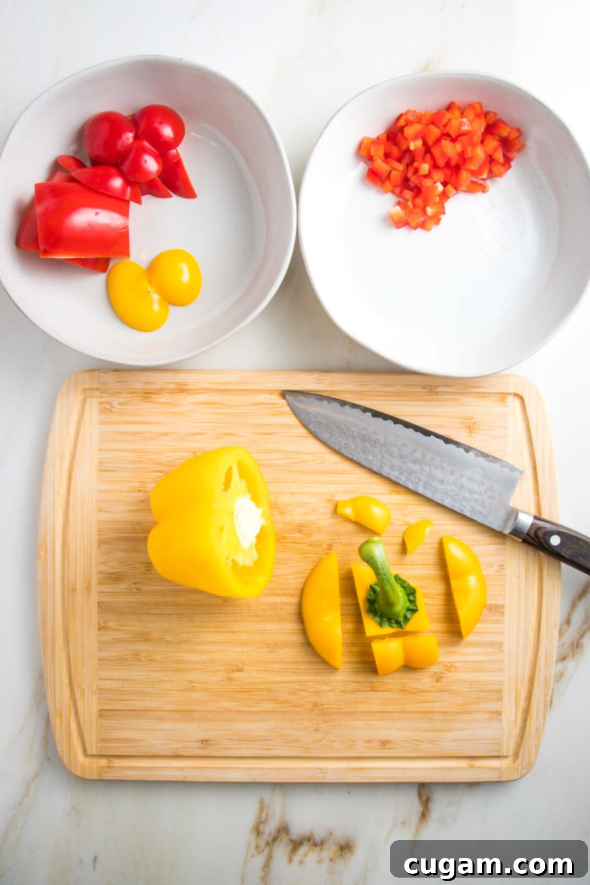 Prepping Veggies: 2 white bowls, one has chunky red and yellow peppers, one has small dice red peppers and the cutting board is a yellow pepper being diced. 