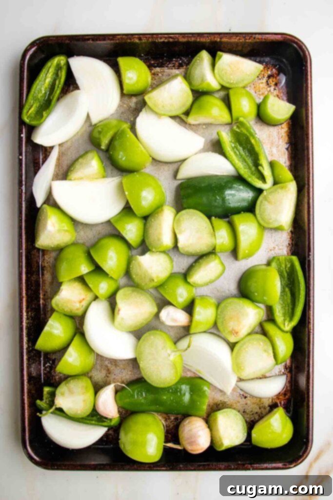 Zesty Roasted Tomatillo Salsa 6 Tomatillos, jalapenos, and onions on a baking sheet before roasting.
